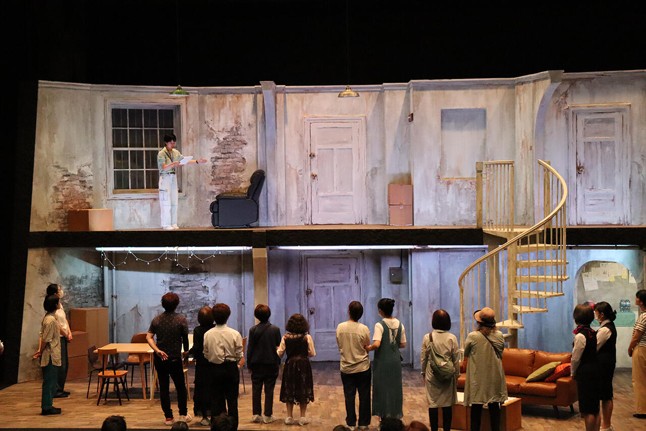 スタッフが舞台美術の上階部分の説明をしている写真